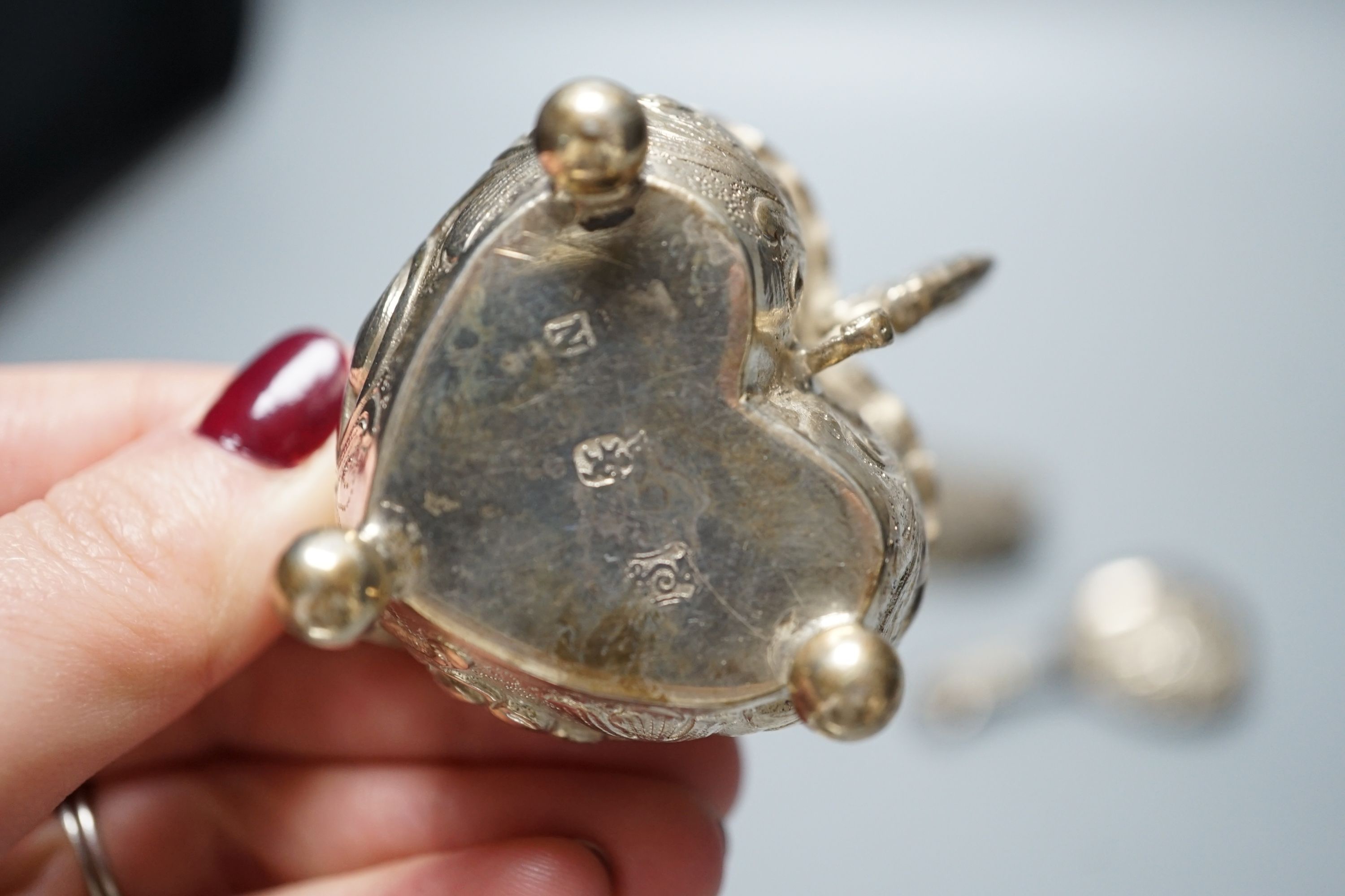A George III silver caddy spoon, with associated bowl, handle marked for John Bettridge, Birmingham, 1817, 76mm, a late 19thcentury Hanau white metal small jug, an embossed white metal heart shape box and a white metal p